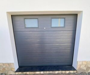 Portão seccionado cinza com 2 sistemas de abertura e fecho sistema automático comando e sistema manual chave para quando há falta de luz.
