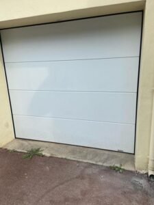 Portão seccionado com painel liso branco.